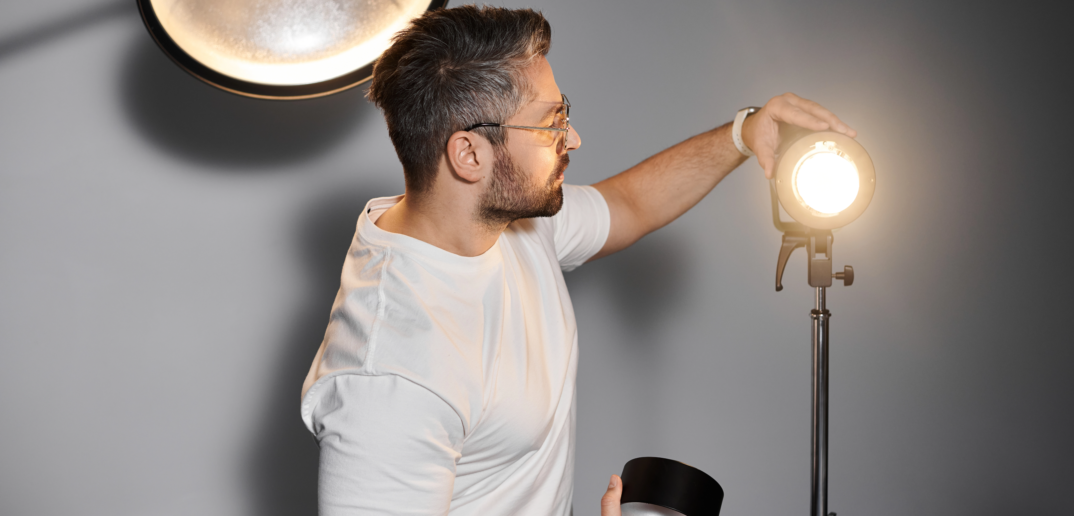 Homme créatif ajustant l'équipement d'éclairage pour une séance photo professionnelle dans un studio moderne