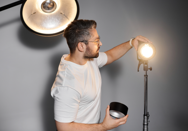 Homme créatif ajustant l'équipement d'éclairage pour une séance photo professionnelle dans un studio moderne