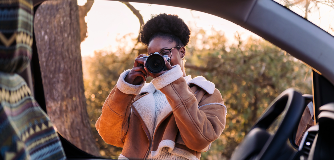 woman taking photos with camera during a road trip