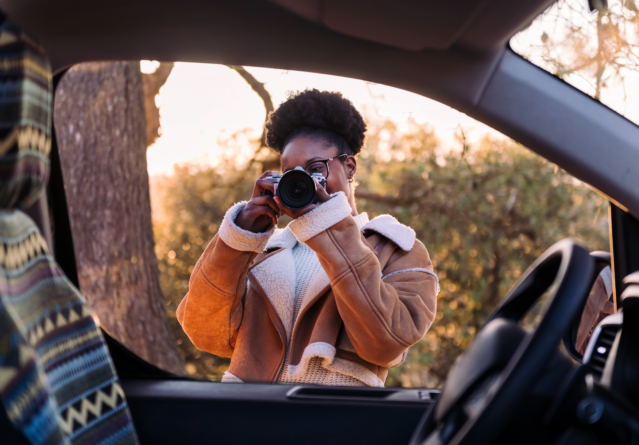woman taking photos with camera during a road trip
