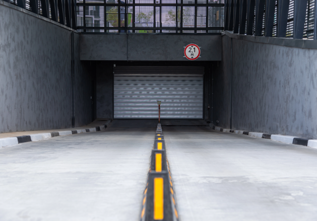 Entrée au parking souterrain avec porte à volet roulant et séparateurs de route